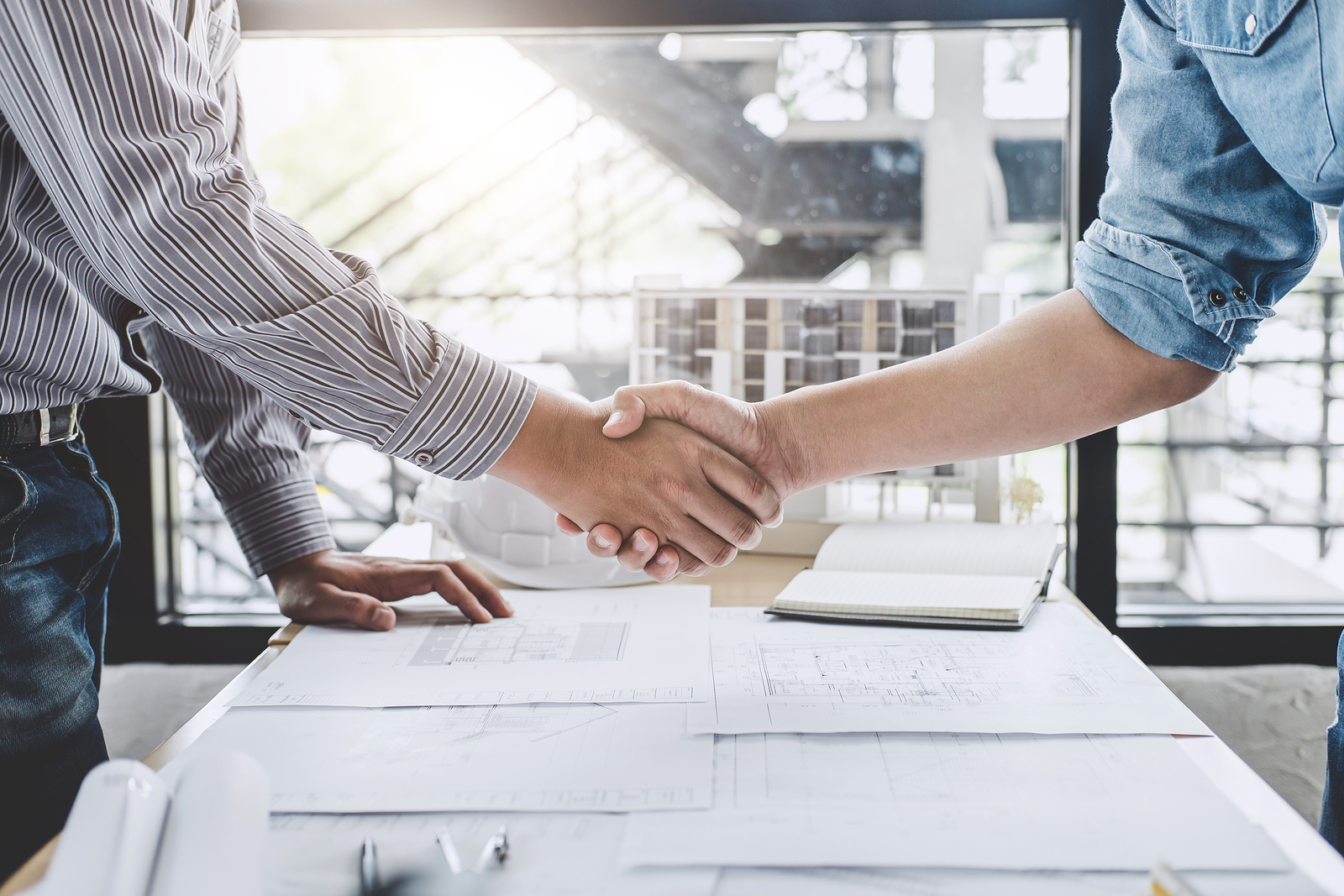 Construction professionals shaking hands over project plans